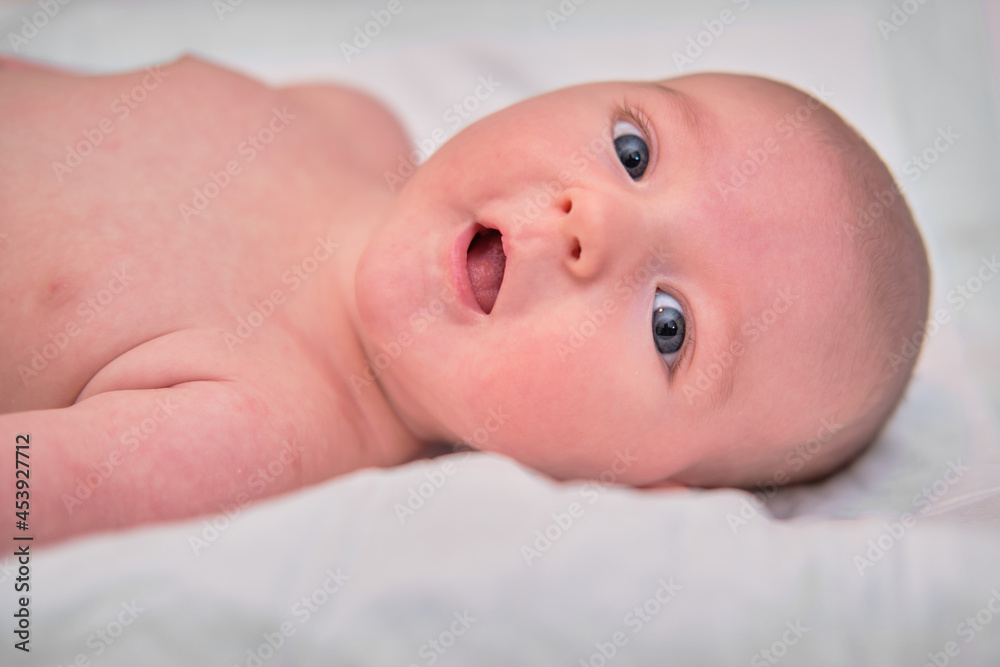 Portrait of a smiling infant baby lying on the bed, close-up. Happy baby boy, face closeup Portrait of a smiling infant baby lying on the bed, close-up. Happy baby boy, face closeup