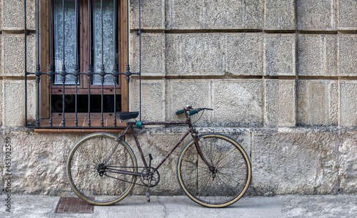 vintage bicycle in poor condition tied to a window grille of a house in a historic district, copy space