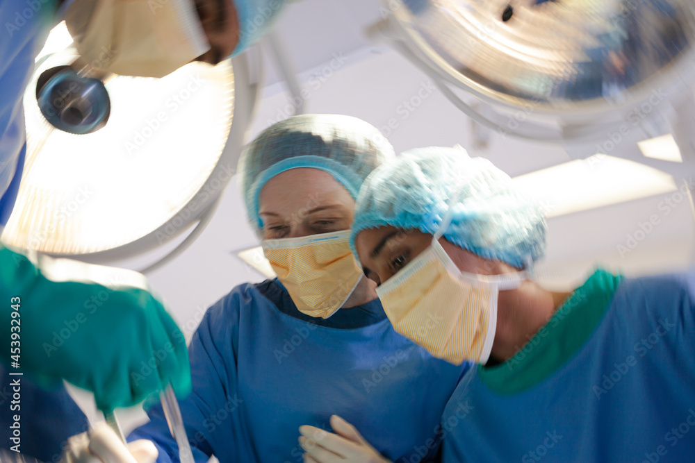 Surgeons bent over patient on operating table Surgeons bent over patient on operating table