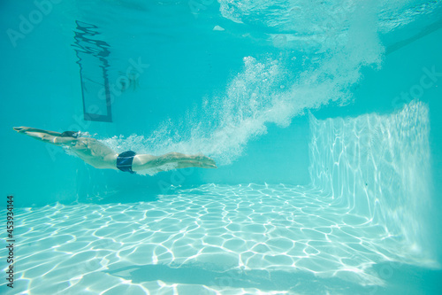 Man swimming underwater in pool