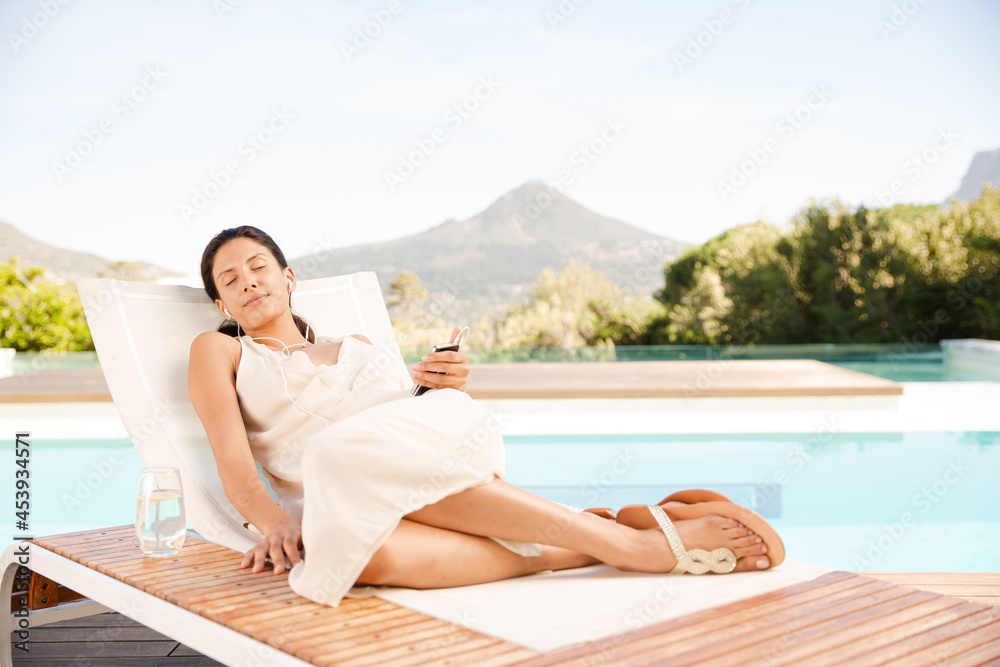 Woman listening to mp3 player at poolside