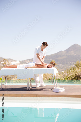 Woman receiving massage poolside at spa © KOTO