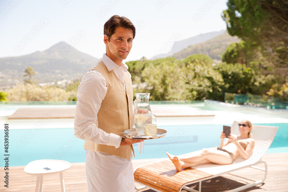 Waiter serving woman at poolside
