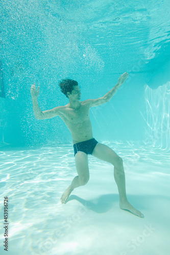 Man posing underwater in swimming pool