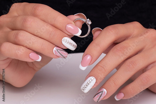 Beautiful female hands with wedding manicure nails with ring on white background