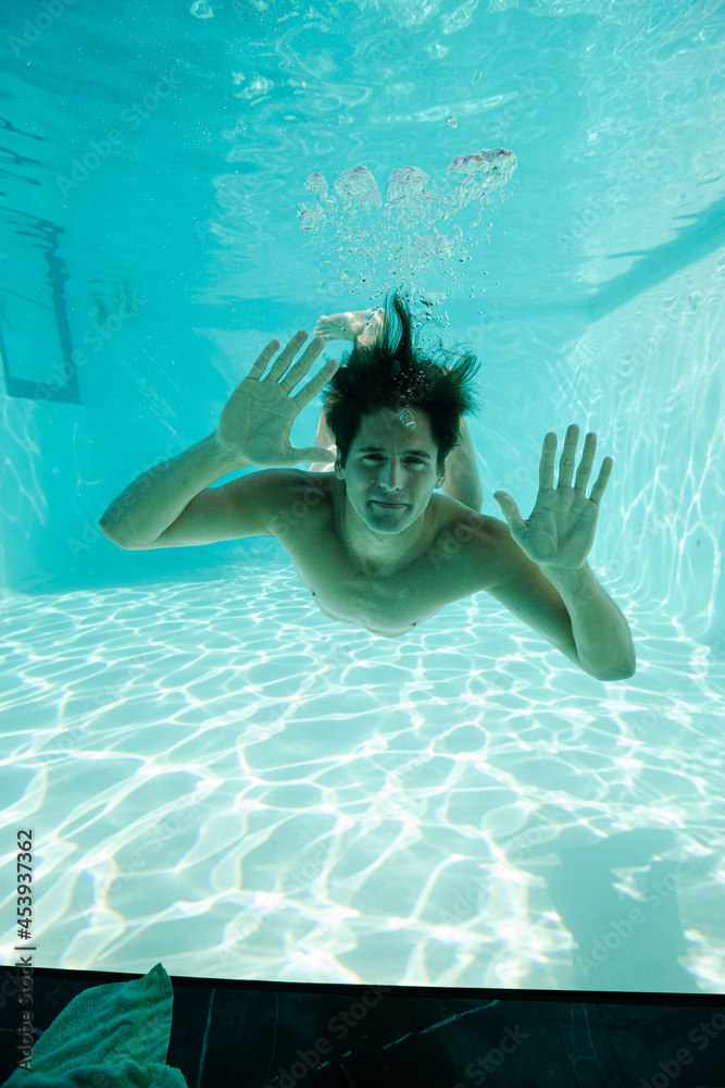 Man looking through window underwater in swimming pool