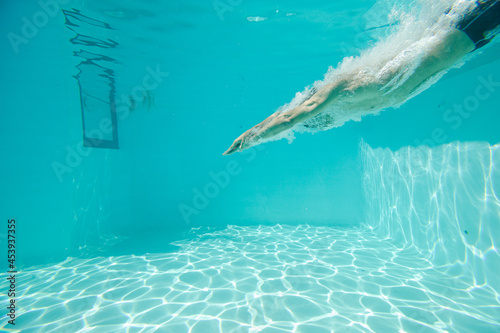 Man swimming underwater in pool