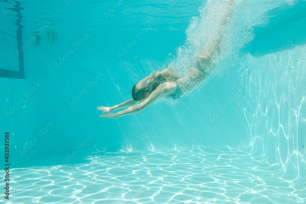 Woman swimming underwater in pool