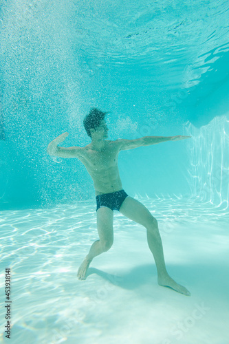 Man posing underwater in swimming pool