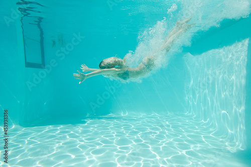 Woman swimming underwater in pool