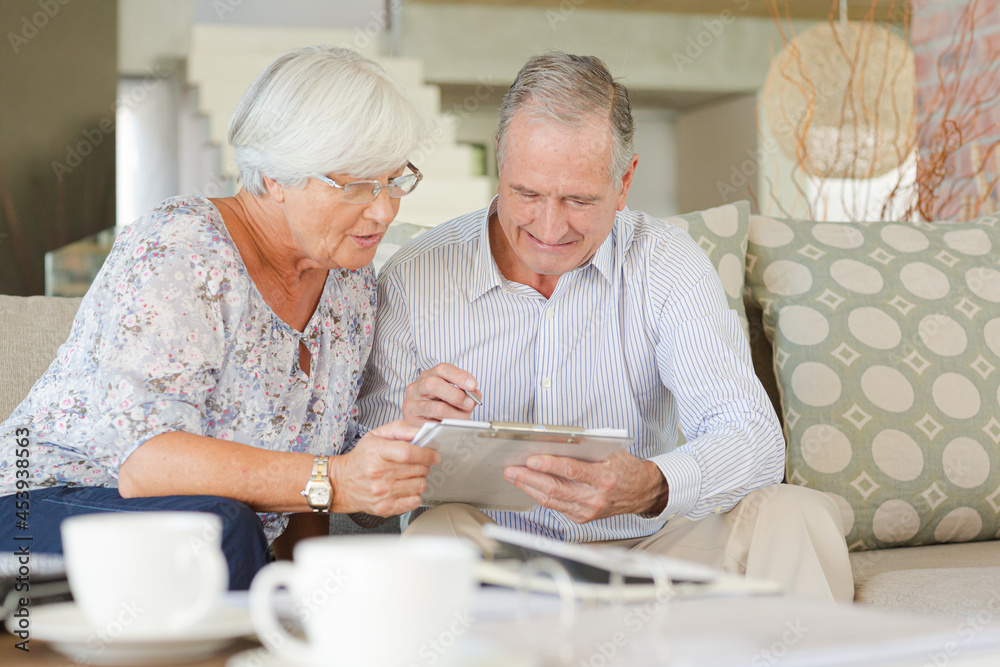 Couple examining blueprints on sofa Couple examining blueprints on sofa