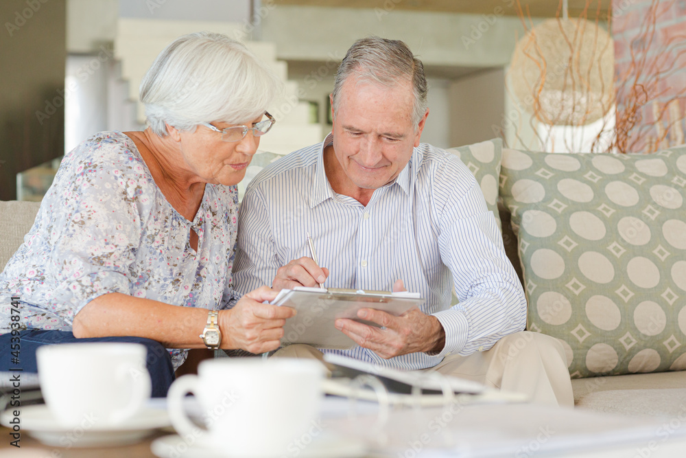 Couple examining blueprints on sofa Couple examining blueprints on sofa
