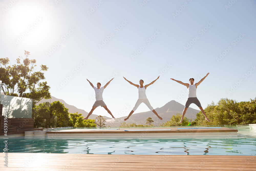 People jumping with arms and legs outstretched at poolside Stock Photo