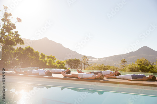 People practicing yoga at poolside