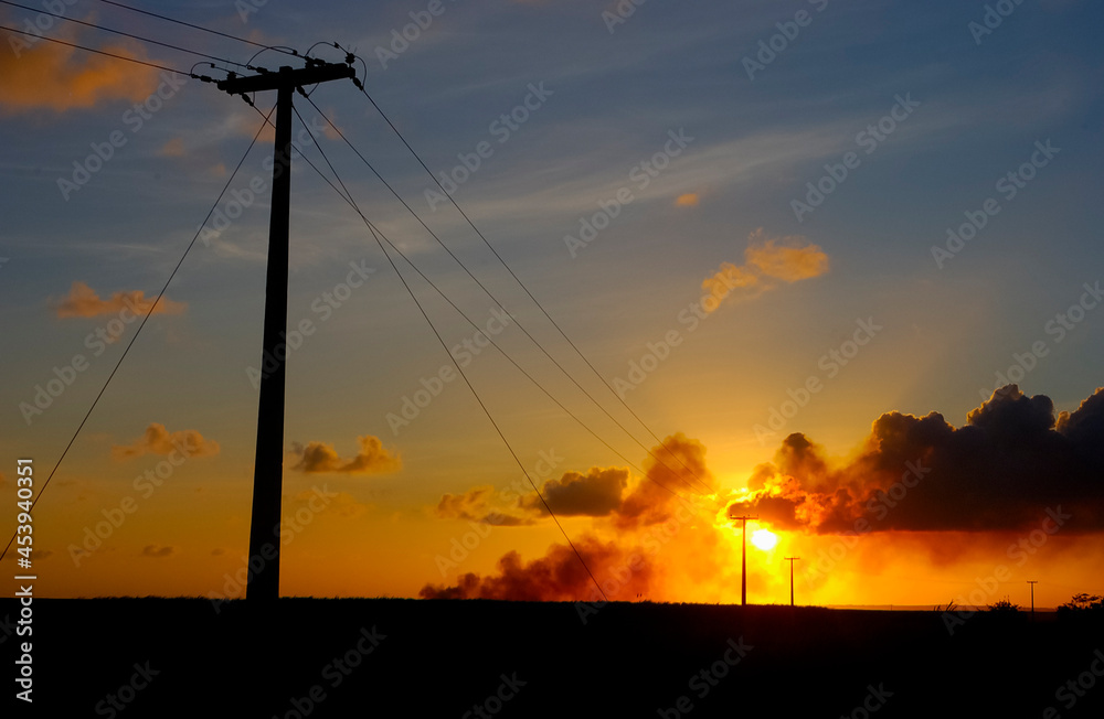 Electrifying posts with orange sunset sky background.