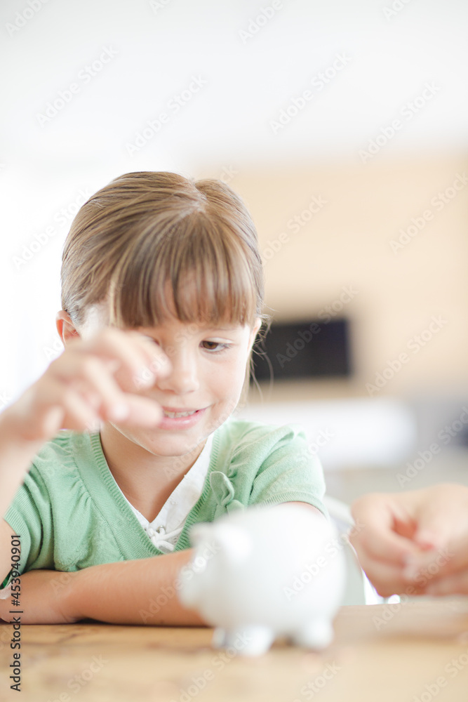 Girl filling piggy bank on counter
