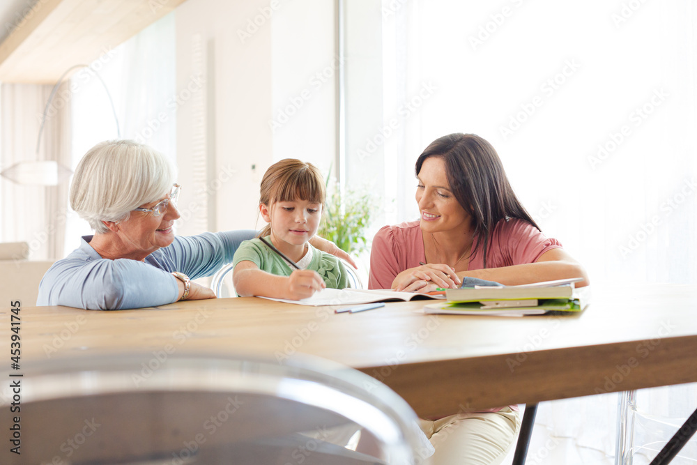 Mother and grandmother helping girl with homework Mother and grandmother helping girl with homework