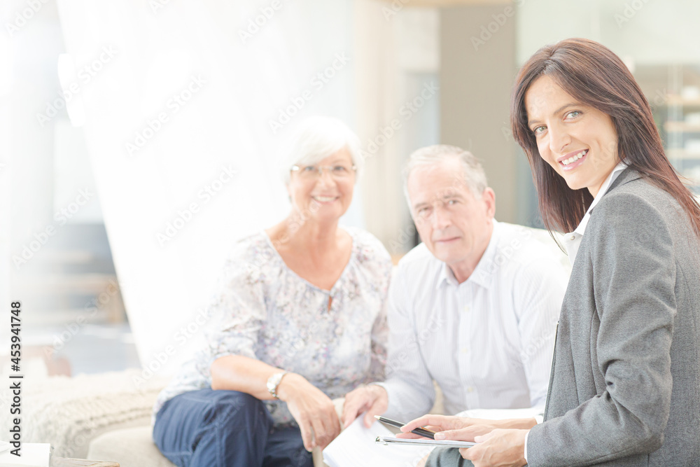 Financial advisor smiling with couple on sofa Financial advisor smiling with couple on sofa
