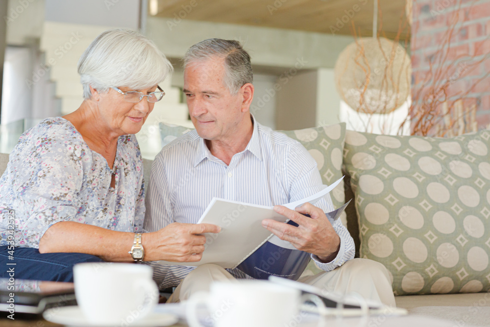 Couple examining blueprints on sofa