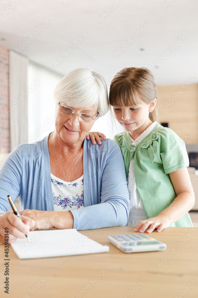 Older woman and granddaughter using calculator Older woman and granddaughter using calculator