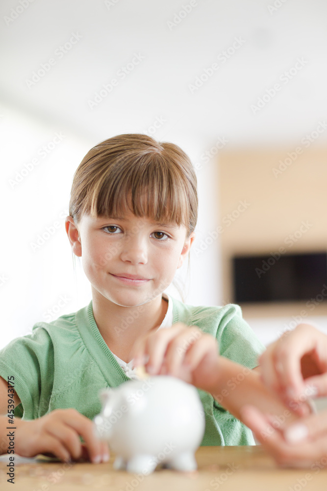 Girl filling piggy bank on counter Girl filling piggy bank on counter