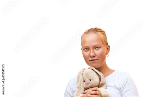 Young blonde girl holds a soft toy in her hands and smiles modestly