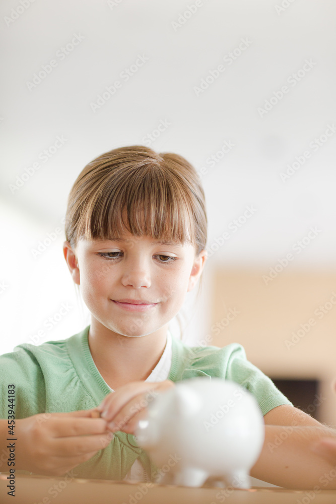 Girl filling piggy bank on counter Girl filling piggy bank on counter