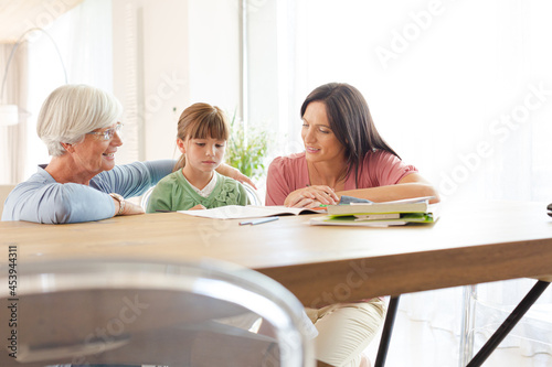 Mother and grandmother helping girl with homework