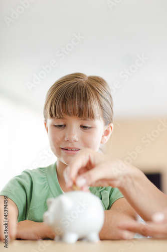 Girl filling piggy bank on counter