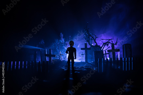 Scary view of zombies at cemetery dead tree, moon, church and spooky cloudy sky with fog, Horror Halloween concept with glowing pumpkin. Selective focus © zef art