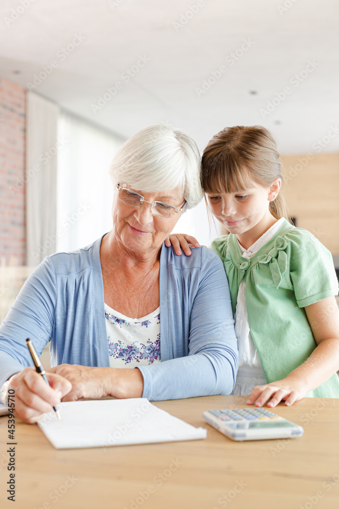 Fototapeta premium Older woman and granddaughter using calculator