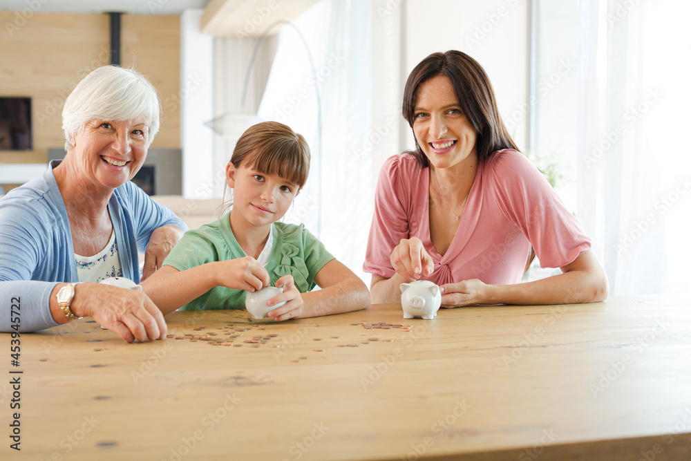 Fototapeta premium Three generations of women filling piggy bank