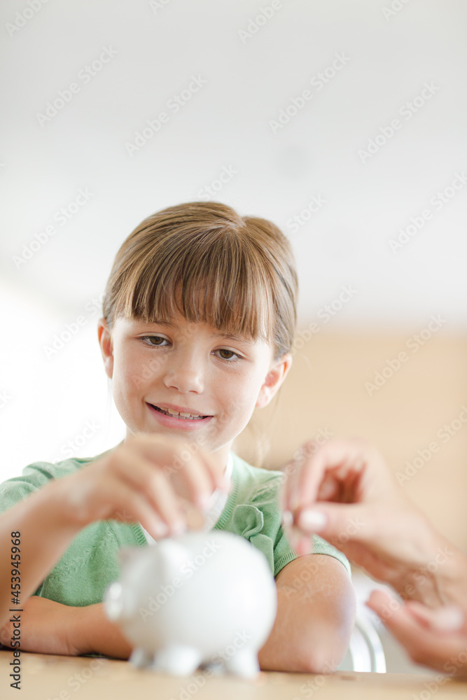 Girl filling piggy bank on counter Girl filling piggy bank on counter