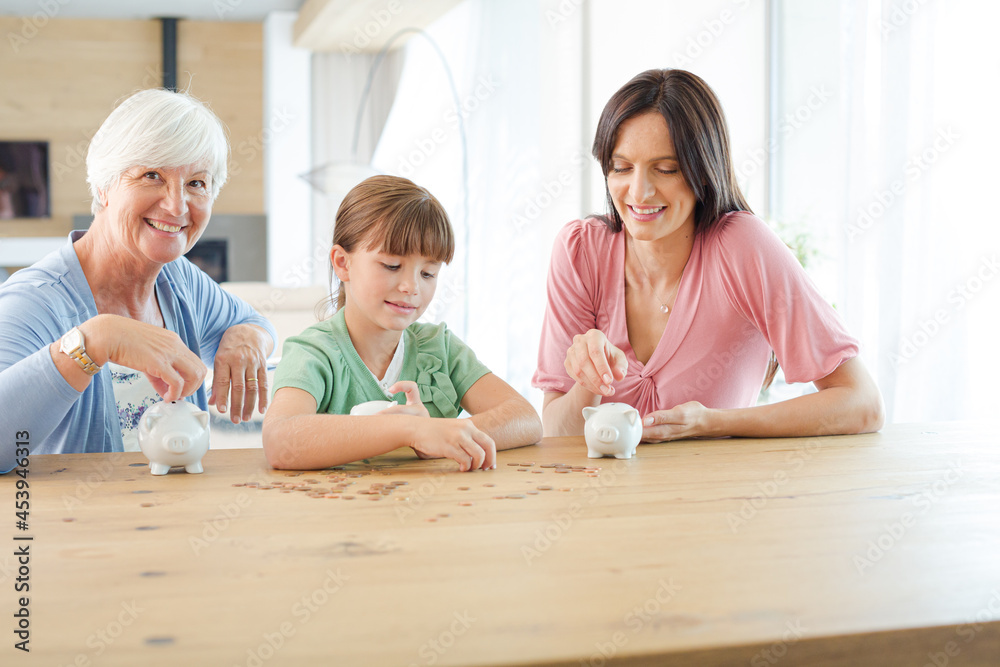 Fototapeta premium Three generations of women filling piggy bank