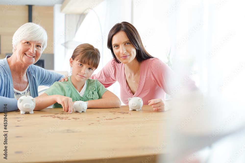 Three generations of women filling piggy bank Three generations of women filling piggy bank