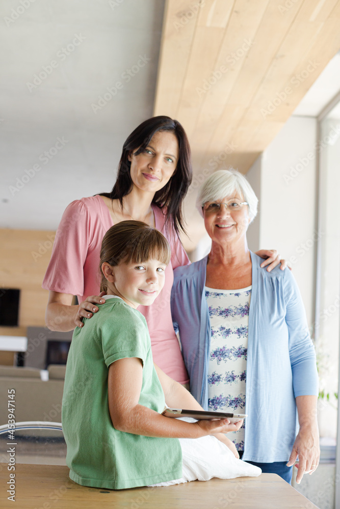 Three generations of women posing in kitchen, smiling