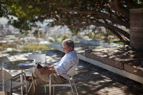 Older man using tablet computer outdoors