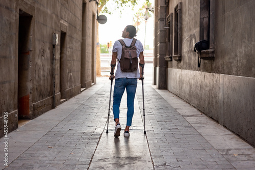 Young latin man with crutches visiting the city
