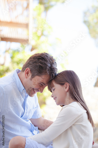 Father and daughter touching foreheads outdoors