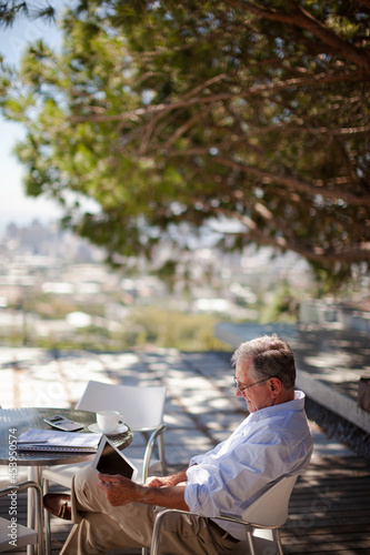 Older man using tablet computer outdoors