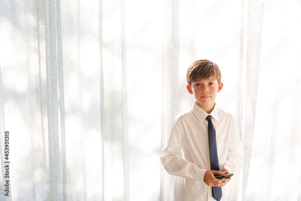 Fototapeta premium Boy in shirt and tie holding smartphone
