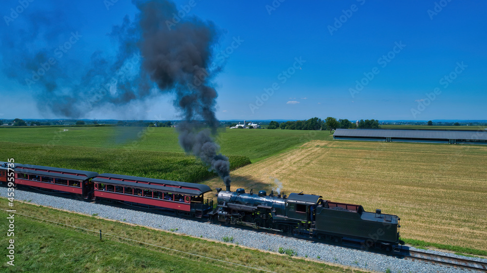 Obraz premium Aerial View of a Steam Locomotive Traveling Across a Fertile Farmland Landscape Blowing Smoke on a Beautiful Summer Day
