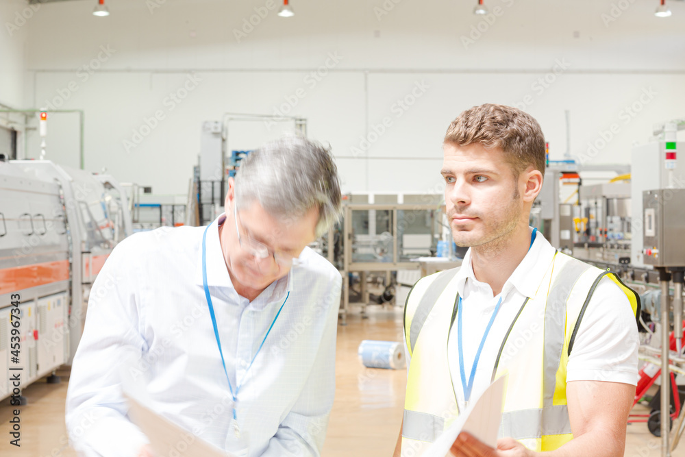 Supervisor and worker reading blueprints in factory Supervisor and worker reading blueprints in factory