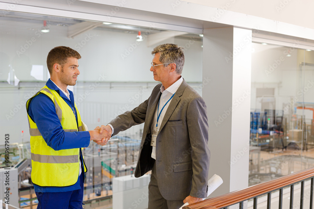 Fototapeta premium Supervisor and worker shaking hands in factory
