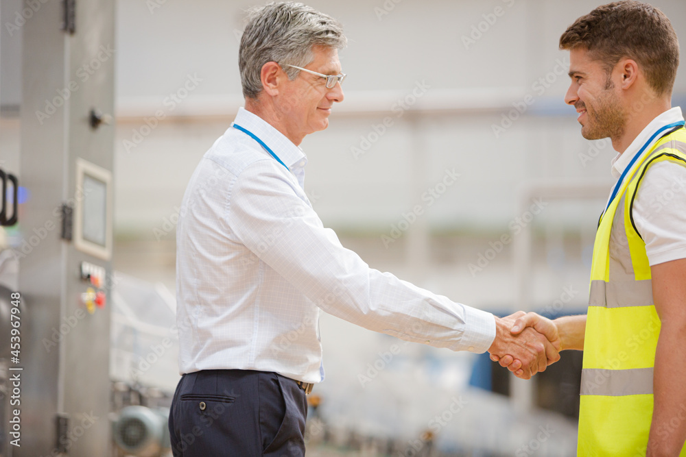 Supervisor and worker shaking hands in factory