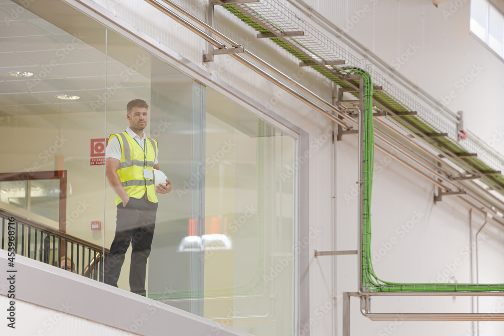 Fototapeta premium Worker looking out glass window in warehouse