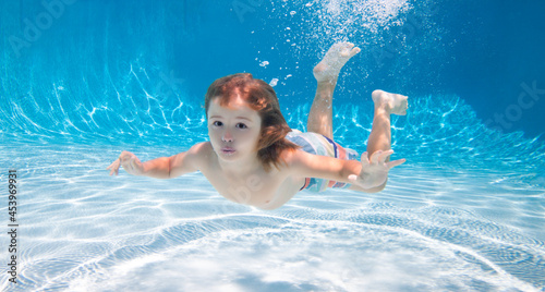 Underwater child swim under water in swimming pool.