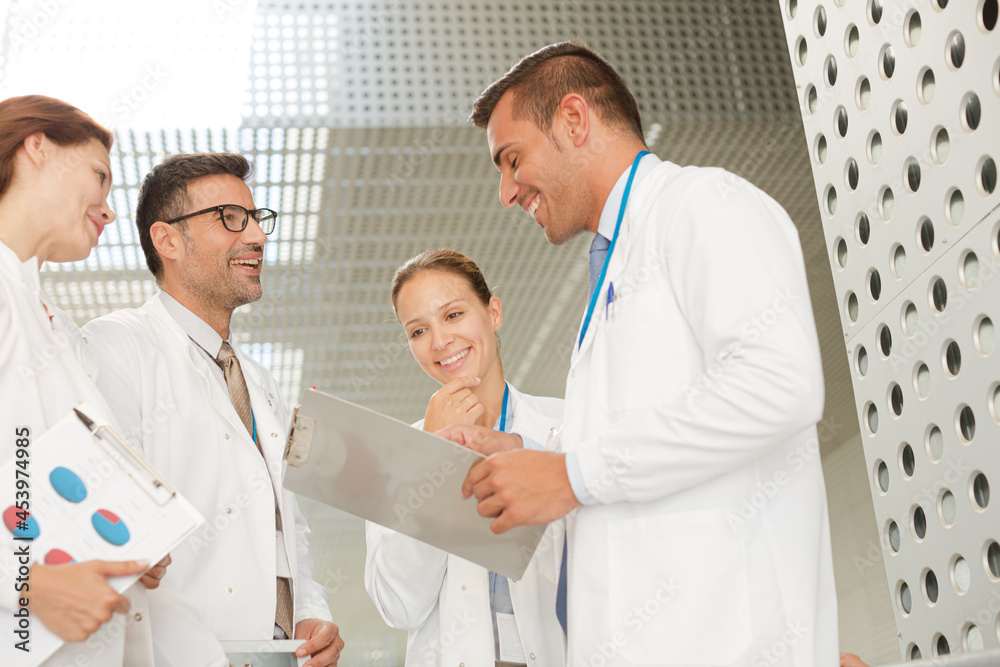Doctors with clipboard talking in hospital corridor Doctors with clipboard talking in hospital corridor