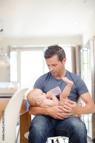 Father feeding baby in kitchen