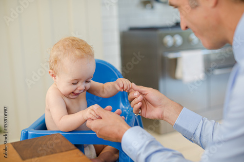 Father playing with baby in high chair